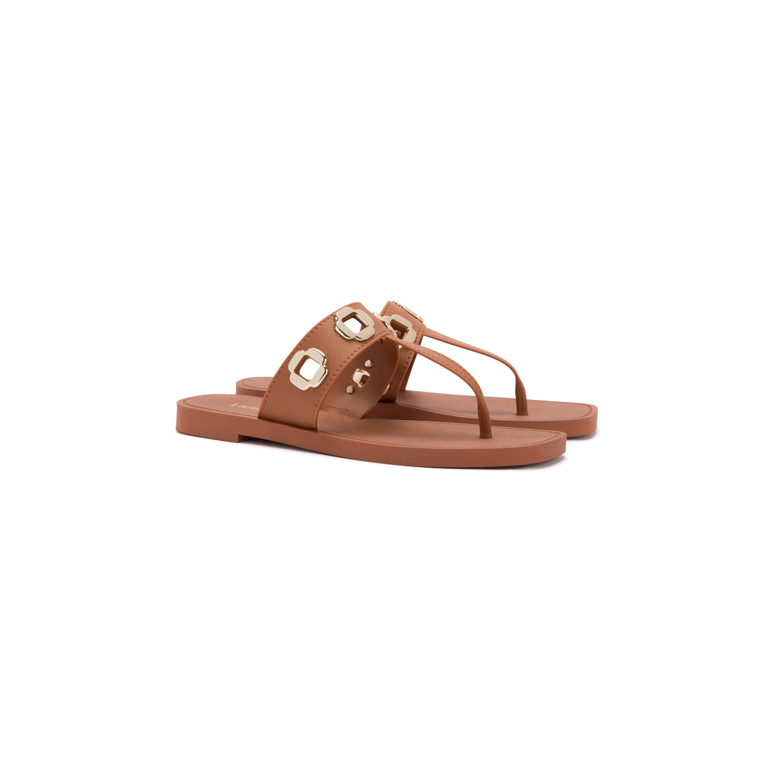 A pair of caramel t-strap sandals with a thick strap over the foot, adorned with large, round, golden embellishments. The Larroudé bestseller, Milan S in Caramel PVC, also features a thong-style strap between the toes. The sandals are set against a plain white background.