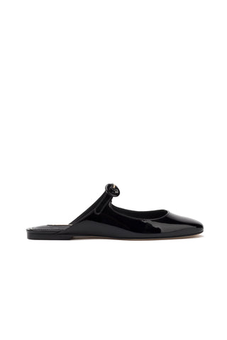 The Blair Flat Mule in Black Patent Leather is depicted against a white background. This sleek shoe boasts a low heel, minimalistic design with a single strap crossing the instep, and an adorable Mary Jane-inspired buckle detail. It features a rounded toe and smooth finish.