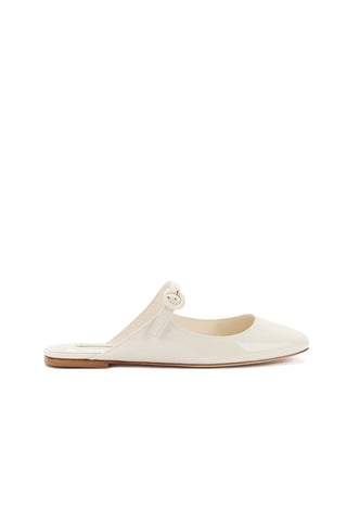 Introducing the Blair Flat Mule in Ivory Patent Leather: a single mule shoe with a pointed toe and an open back, featuring a low heel and a strap with a round buckle on the upper side. The shoe has an appealing patent leather finish and exudes a minimalist, yet elegant design.