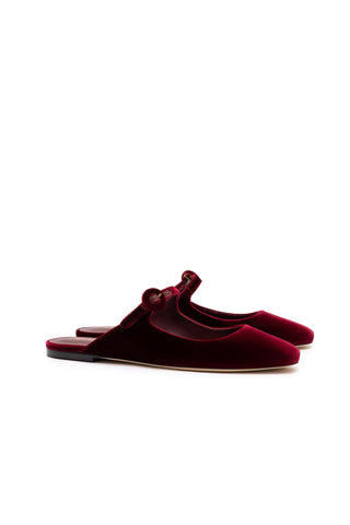 The Blair Flat Mule in Wine Velvet combines elegance with comfort, featuring a backless design and rounded toes. Each shoe showcases a single decorative button on the side of the strap, enhancing its refined and stylish appearance. The memory foam cushion ensures comfort, making them ideal for any occasion.