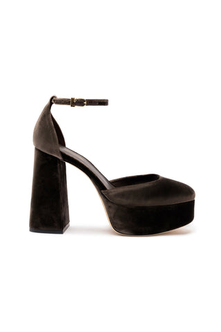 The Ari Pump In Expresso Velvet is a sleek and elegant shoe featuring a single dark brown velvet mary jane platform heel with a 4.5-inch block heel. It has an adjustable ankle strap fastened by a small gold buckle and a rounded closed toe.