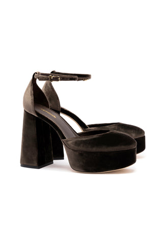 A pair of Ari Pump in Expresso Velvet platform heels, featuring an adjustable ankle strap with a gold buckle, a thick sole, and rounded toe. They have a striking dark brown color with a 4.5-inch block heel and are displayed against a plain white background.