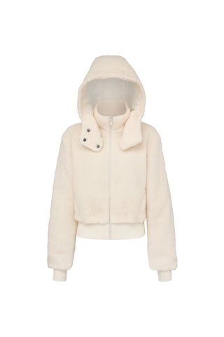 Introducing the Bianca Sherpa Jacket - Snow by Noli Yoga, a cozy cream-colored, fluffy Sherpa jacket with a high collar and front zipper. This stylish jacket features ribbed cuffs and waistband, along with an additional snap button detail on the collar for added warmth and style. Plus, its removable hood makes it perfect for cold weather.