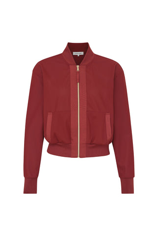 The Wynn Jacket - Merlot is a red bomber jacket with a front zipper and two pockets. It features luxury gold hardware and a ribbed collar, cuffs, and hem, adding a structured look to the design.