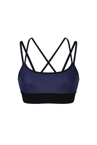 The Liquid Jolie Bra - Navy is a stylish sports bra that combines function and fashion, featuring black accents. It has narrow black straps arranged in a crisscross pattern on the back and a wide black band under the bust for enhanced support. Made with moisture-wicking fabric and 4-way stretch material, this bra guarantees comfort during any workout.