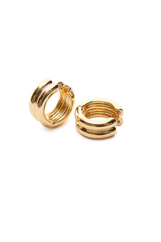 The Colette Hoop Earrings - Gold are showcased against a plain white backdrop. One earring is positioned upright, while the other rests on its side, highlighting their polished finish and triple-band design that adds a modern, stylish flair.