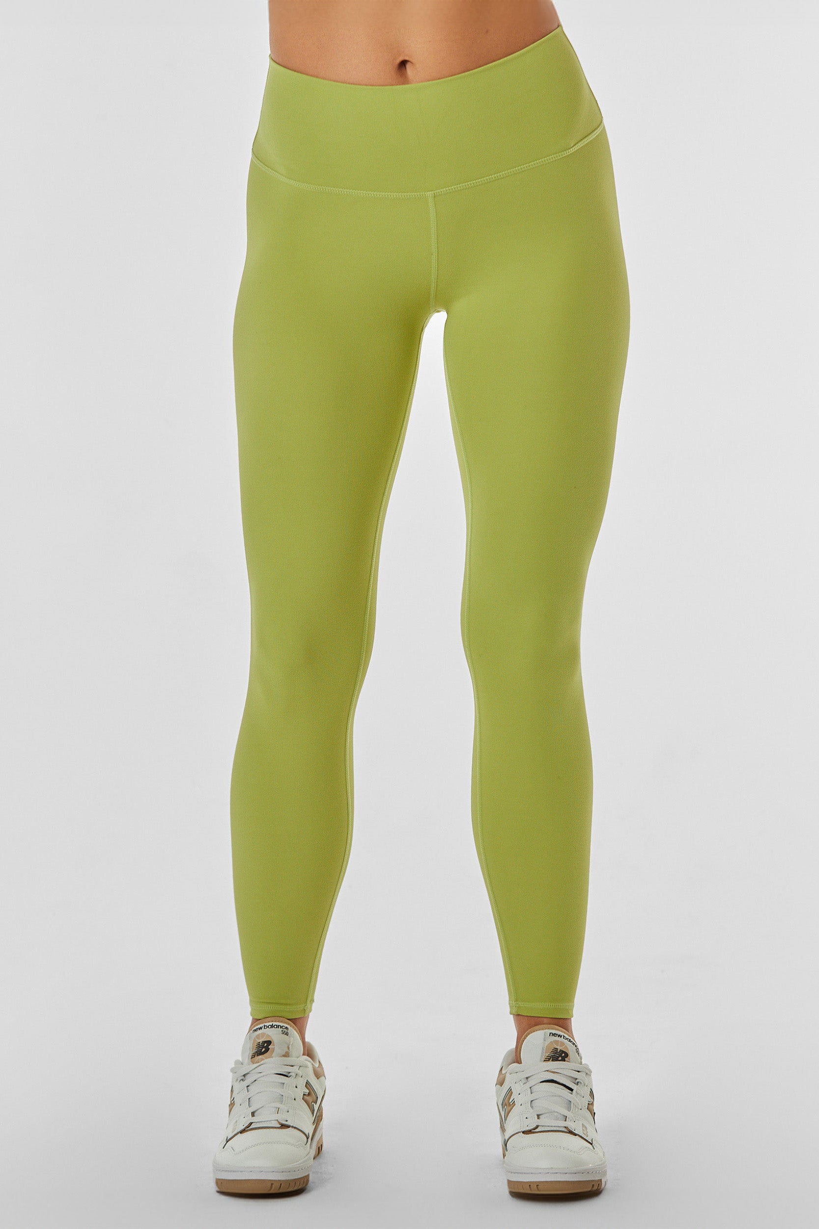 A person wearing the Limitless Legging in Matcha, which are light green, high-waisted, and sculpting, along with white sneakers. The photo is cropped from the waist down, showcasing the full length of the moisture-wicking leggings and shoes against a plain white background.