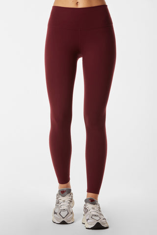 A person is wearing the Limitless Legging in Pinot and white athletic shoes. The photo is cropped just above the waist and below the ankles, displaying only the legs and feet against a plain white background.