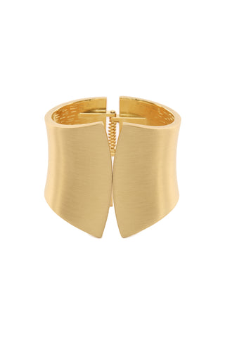 The Lina Bangle - Gold is a wide cuff bracelet with a smooth matte finish. This statement piece features a unique design where the two ends slightly separate at the front, creating a modern and elegant look.