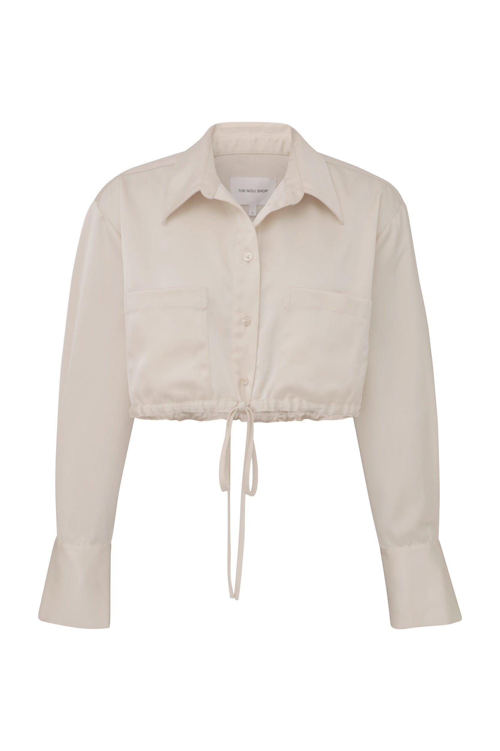 Introducing the Milan Satin Button Up in Pearl: an off-white, long-sleeve cropped blouse featuring a button-down front and two chest pockets with cargo detailing. This satin design includes a pointed collar, wide cuffs, and a tie-waist for an adjustable fit.