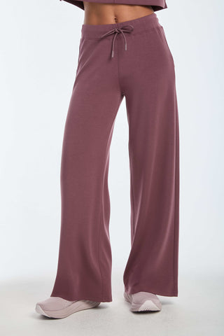 Luxuriously comfortable in wide-legged, high-waisted Daphne Pant - Orchid, crafted from a soft modal blend with drawstring tie, paired with crisp white sneakers. The emphasis is on the lower half of the body set against a plain white background.