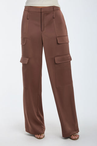 A person models the Milan Satin Cargo Pant in Mocha, showcasing its wide-legged style with multiple pockets. They're standing against a plain white background, paired with open-toed sandals and a light-colored top for a relaxed yet trendy look.