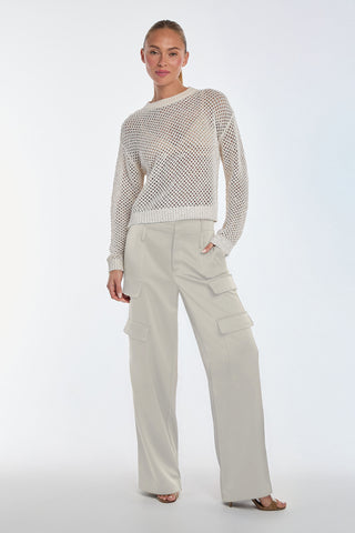 A person exudes chic style, donning the Lucie Sequin Crochet Top in Pearl and beige cargo pants with side pockets. Against a plain, light background, they pose with hands by their sides and one foot slightly forward.