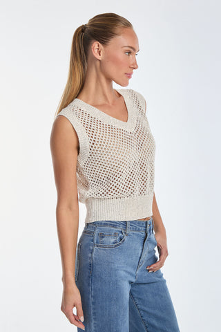 A person with long hair in a ponytail is wearing the Addison Sequin Crochet Top in Pearl and blue jeans, standing sideways to the camera against a plain white background.