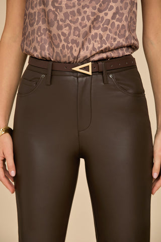 A person wearing a leopard print top and dark faux leather pants is accessorized with the Amelia Belt in Espresso, known for its polished hardware. The image emphasizes the fashionable lower half of this ensemble.