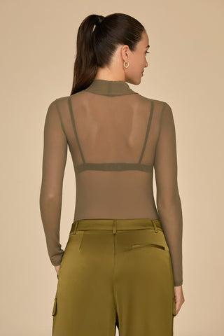 A person with long hair in a ponytail is wearing the Giselle Bodysuit in olive mesh, paired with olive green pants featuring pockets. They are facing away, standing against a plain light brown background.