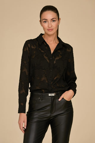 A person wearing a black Stelle Lace Blouse and black leather pants stands against a neutral background. They have one hand in a pocket and a calm expression.