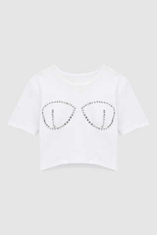 The Rya Crystal T-Shirt in white is a chic cropped top with a bustier design, featuring hand-beaded crystal details that form a stylish rhinestone outline of a bra on the front.