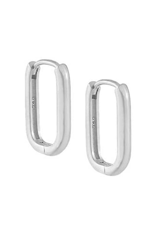 The Solid Oval Huggie Earring by By Adina Eden features sleek, oval sterling silver hoops with rounded corners. The metallic surface is smooth, and each earring has a clasp mechanism at the top for securing when worn. The inner part of these huggie earrings is stamped with "925", indicating their high-quality material.