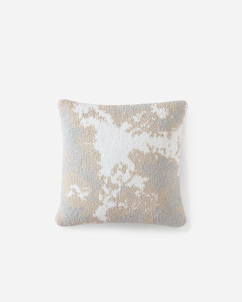 A square throw pillow against a plain white background. The Pixel Throw Pillow by Sunday Citizen features a textured abstract pattern in beige, white, and light blue hues, resembling a soft cloud-like formation. The snug fabric combined with the memory foam filling ensures maximum comfort for any setting.